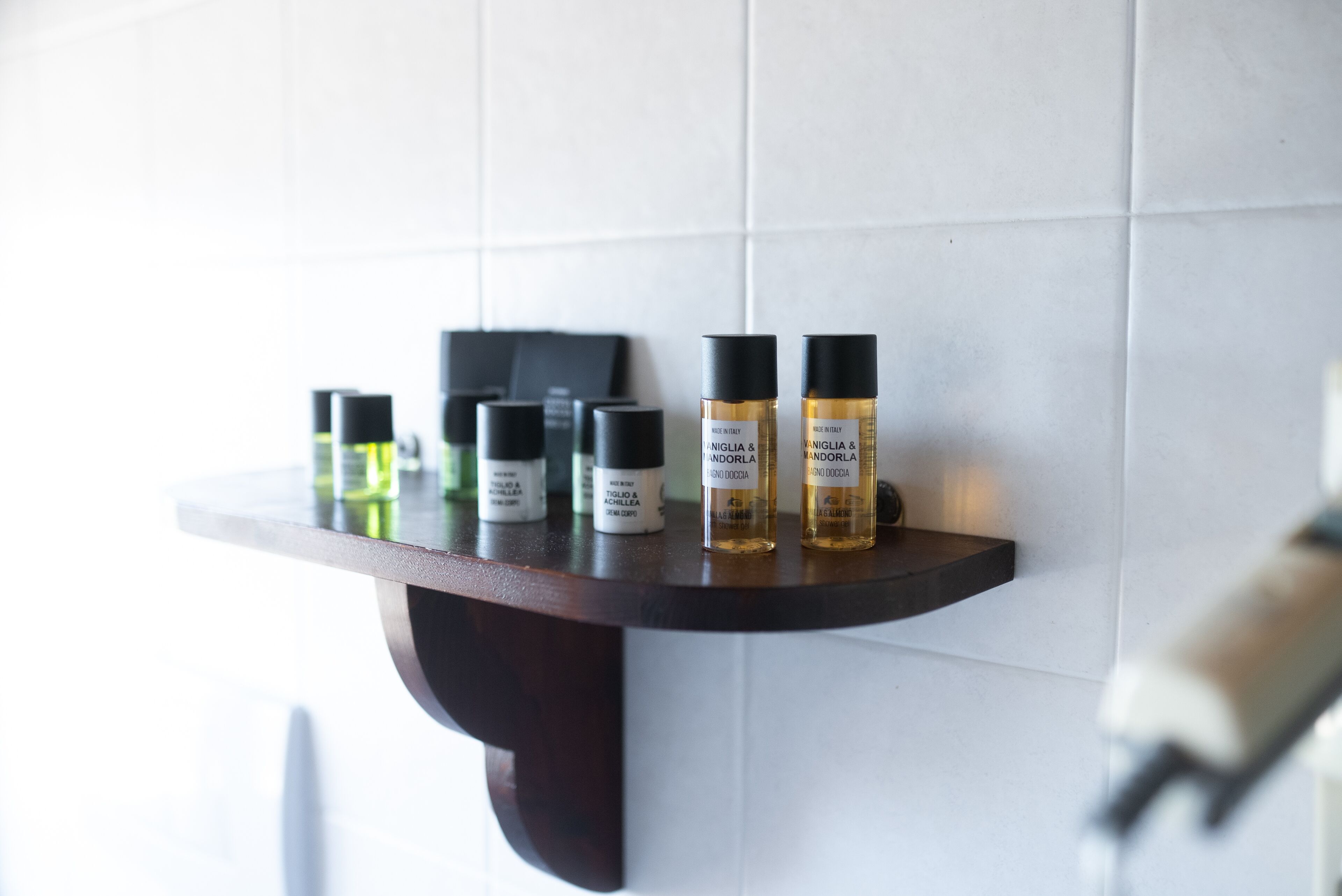 Una estantería con varias botellas de productos frente a un muro de azulejos.