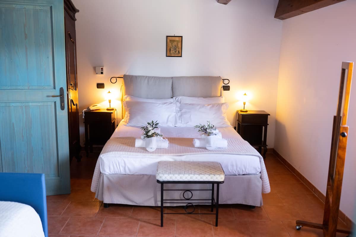 A bedroom with a bed, bedside tables, a bench, and a door.