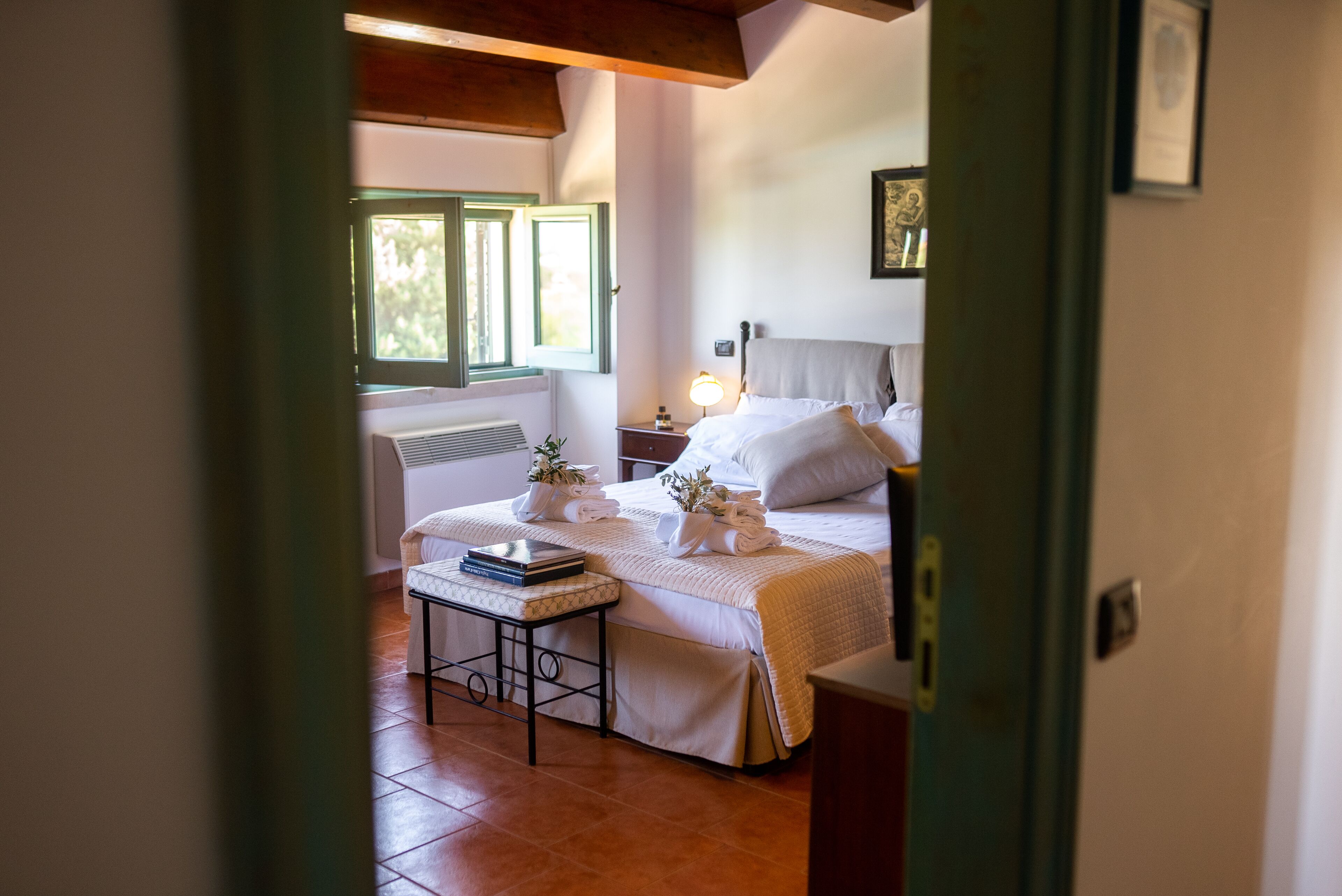 A bedroom with a bed, bedside table, and a window with shutters.