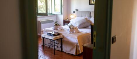A bedroom with a bed, bedside table, and a window with shutters.
