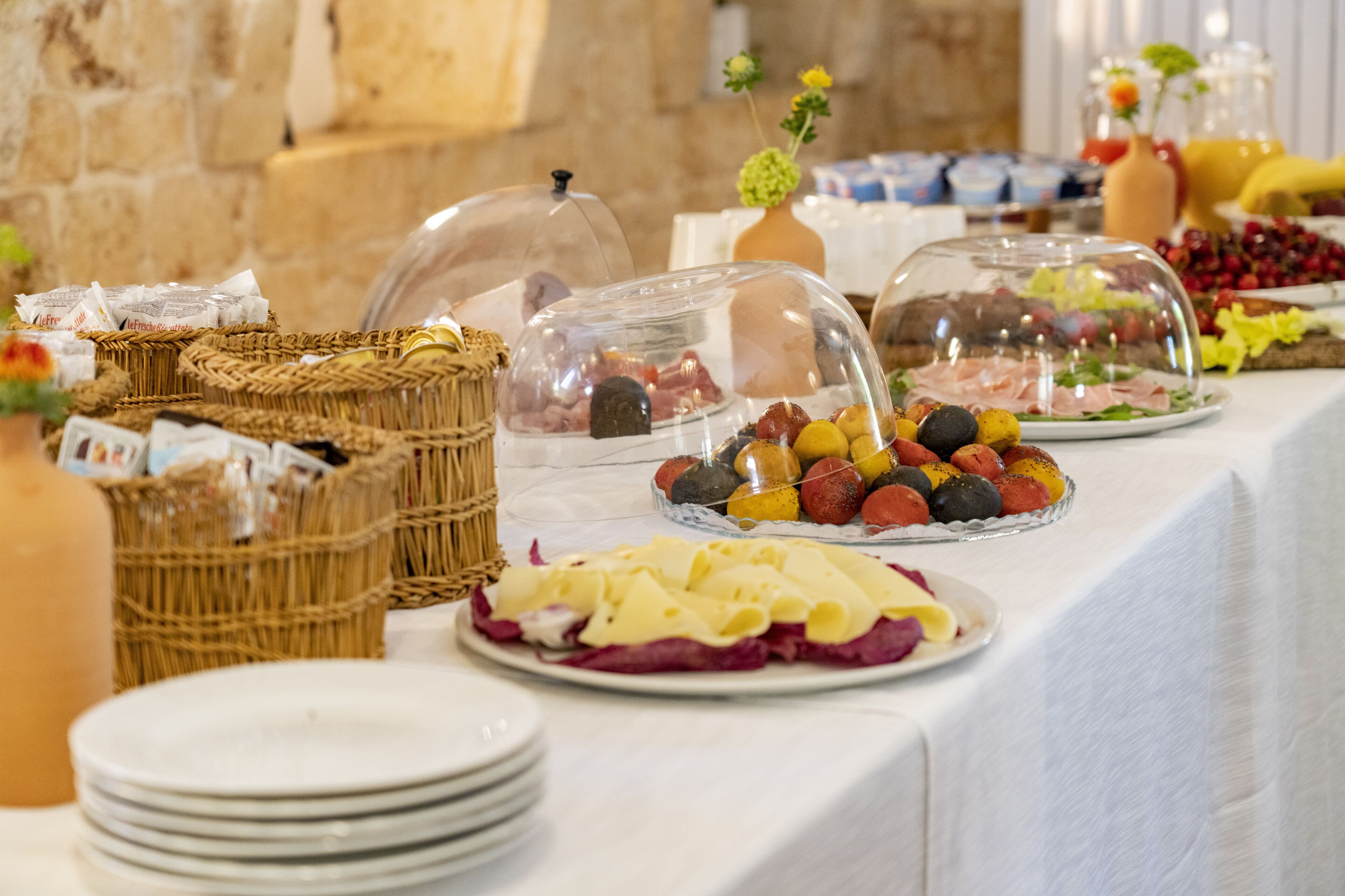 A buffet with various food items, including fruits, cheeses, and meats, covered with glass domes.