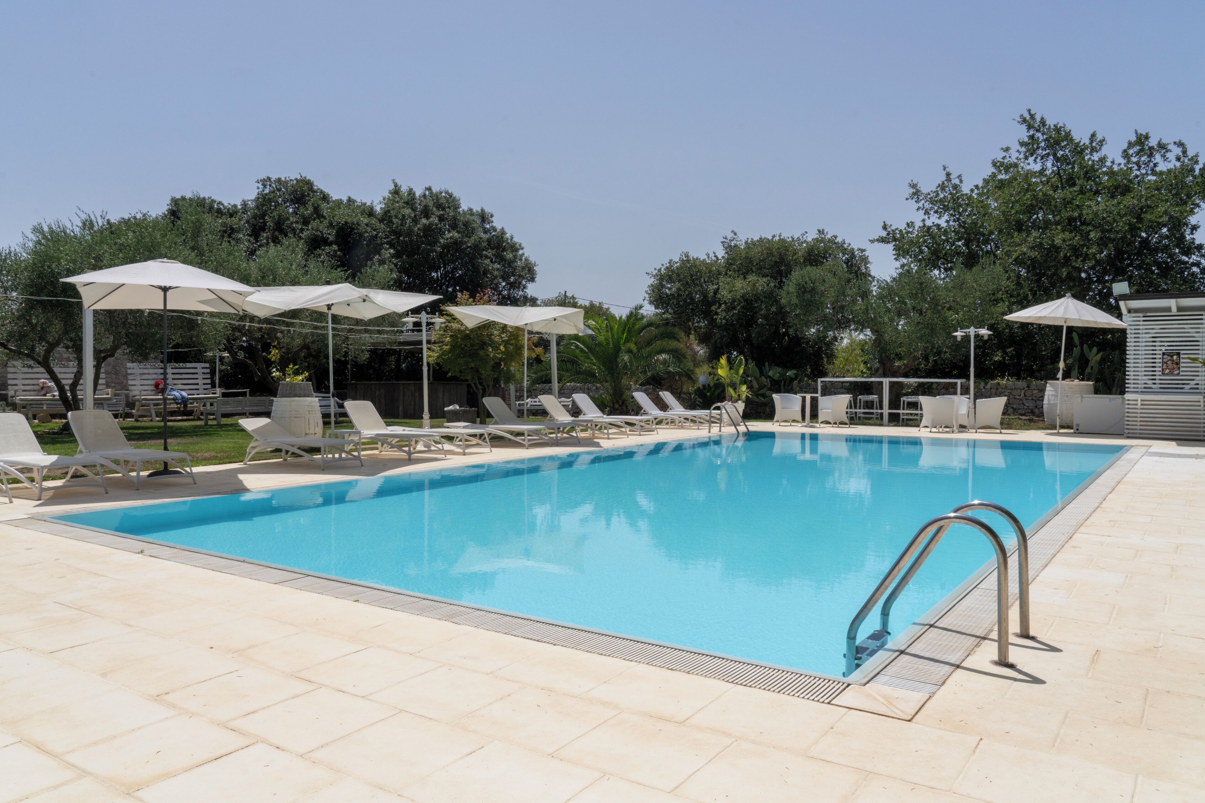 Une piscine avec des chaises longues et des parasols.