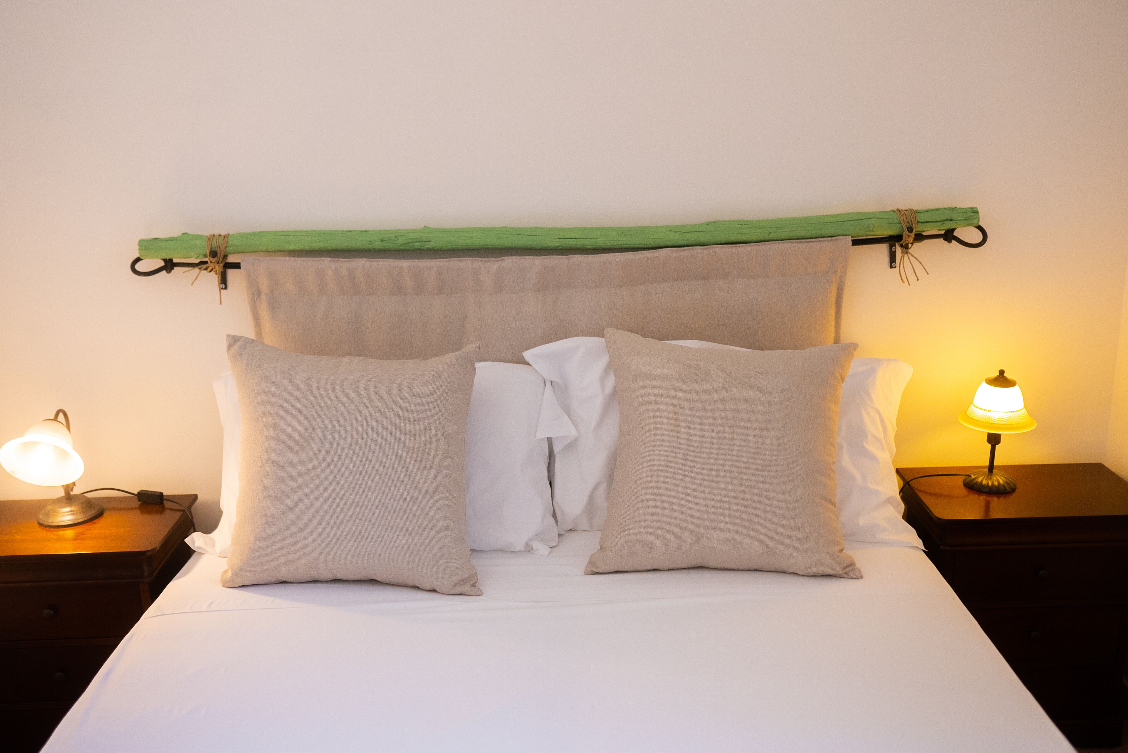A bed with white bedding, two bedside lamps, and a green headboard.