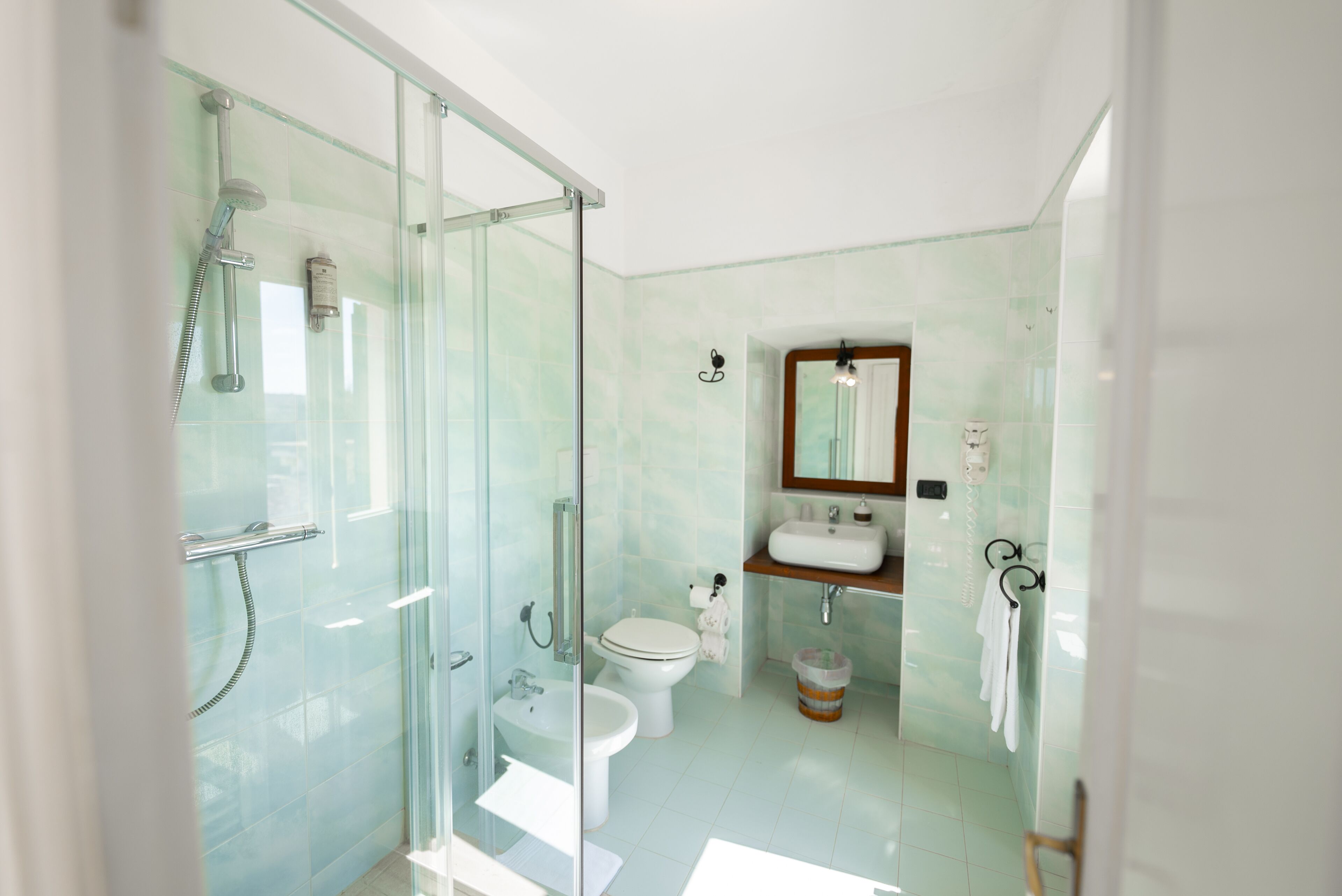 A modern bathroom with a glass-enclosed shower, a toilet, a sink, and a mirror.