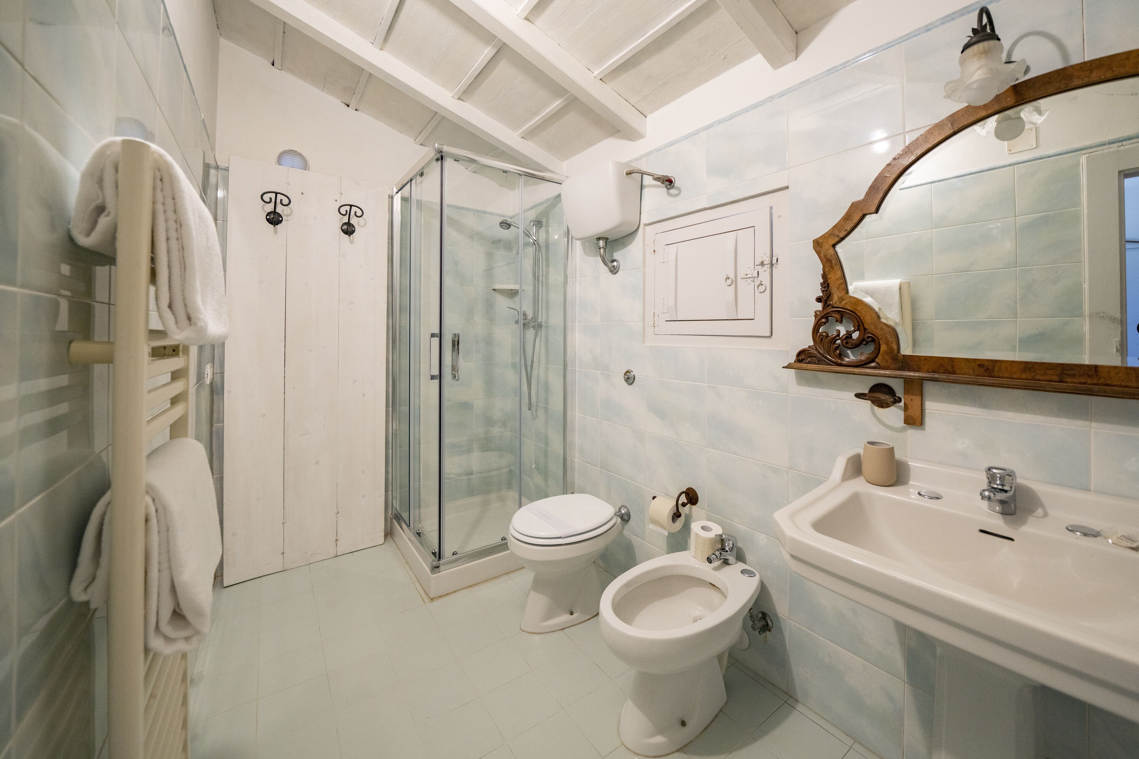 Ein Badezimmer mit Duschkabine, Toilette, Bidet und Waschbecken mit Spiegel darüber.