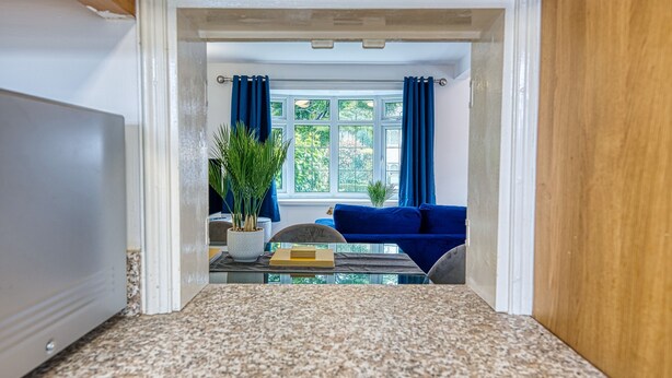 Une pièce comprenant une table à manger, des chaises, un canapé bleu et une fenêtre avec des rideaux.