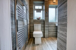 Une salle de bain moderne avec des toilettes, une fenêtre offrant une belle vue et un panneau décoratif au-dessus des toilettes.