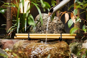 Una fuente de bambú con agua fluyendo sobre rocas en un jardín.