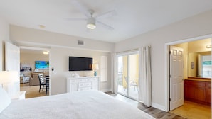 A spacious bedroom with a large bed, a ceiling fan, a TV, and a sliding glass door leading to a balcony. - Beach Views, Steps to the Beach Access. Waterfront Resort Heated Pool & Hot Tub. Fishing Dock. (Treasure Island)