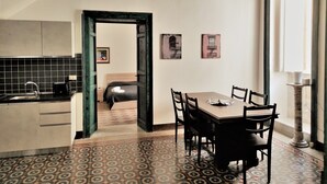 A modern kitchen with a tiled backsplash, a dining area with a patterned floor, and a hallway leading to a bedroom. - Residenza Diana (Syracuse)