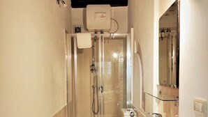 A bathroom with a glass-enclosed shower, a toilet, and a sink. - Residenza Diana (Syracuse)