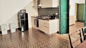A kitchen with a gas stove, oven, and microwave. There are cabinets and a tiled backsplash. - Residenza Diana (Syracuse)