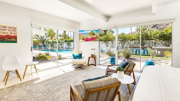 A modern living room with large windows, a pool view, and a comfortable seating area. - REGAL Palm Springs - Palm Springs Paradise: Your Private Poolside Retreat Awaits (Palm Springs)