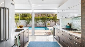 A modern kitchen with a large island, a built-in oven, and a view of a swimming pool. - REGAL Palm Springs - Palm Springs Paradise: Your Private Poolside Retreat Awaits (Palm Springs)