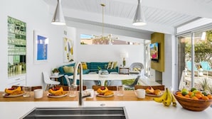 A modern kitchen with a central island, a dining area with a round table, and a living space with a sofa and chairs. - REGAL Palm Springs - Palm Springs Paradise: Your Private Poolside Retreat Awaits (Palm Springs)