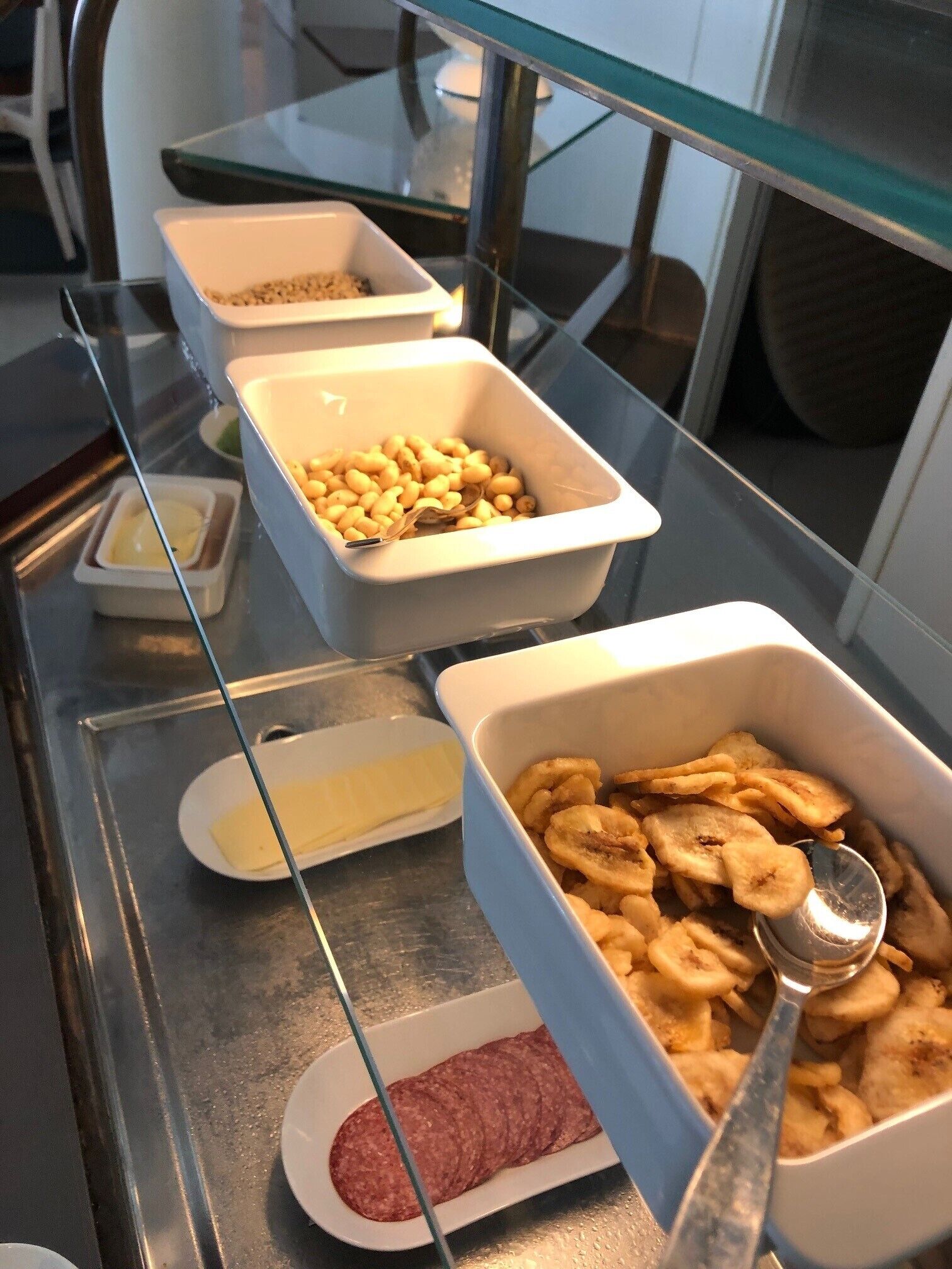 A buffet with various food items including beans, banana slices, and a dish of sliced meat.