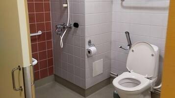 Een kleine badkamer met toilet, douche en een handgreep.