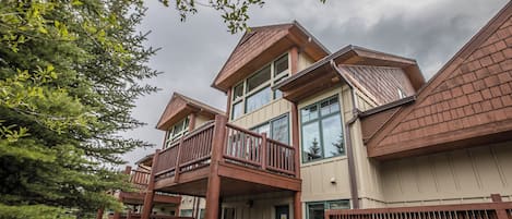 Un immeuble résidentiel à plusieurs étages, doté d’un balcon, de fondations en pierre et d’une façade en bois.