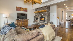 Ein gemütliches Wohnzimmer mit Kamin aus Stein, einer Ledersofa und einem Flachbildfernseher.