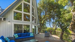 A deck with outdoor furniture, a large window, and a view of trees. - Alexander Valley Russian River Home for 8, Spa, WiFi, BBQ, bocce, vineyard (Cloverdale)
