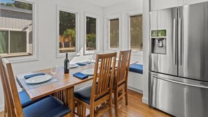 A dining area with a wooden table and chairs, a stainless steel refrigerator, and windows with views of greenery. - Alexander Valley Russian River Home for 8, Spa, WiFi, BBQ, bocce, vineyard (Cloverdale)