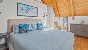 A bedroom with a large bed, a wooden ceiling, a painting on the wall, and a dresser. - Alexander Valley Russian River Home for 8, Spa, WiFi, BBQ, bocce, vineyard (Cloverdale)
