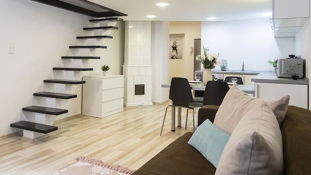 Um apartamento moderno com escada, sala de jantar e sala de estar com sofá.