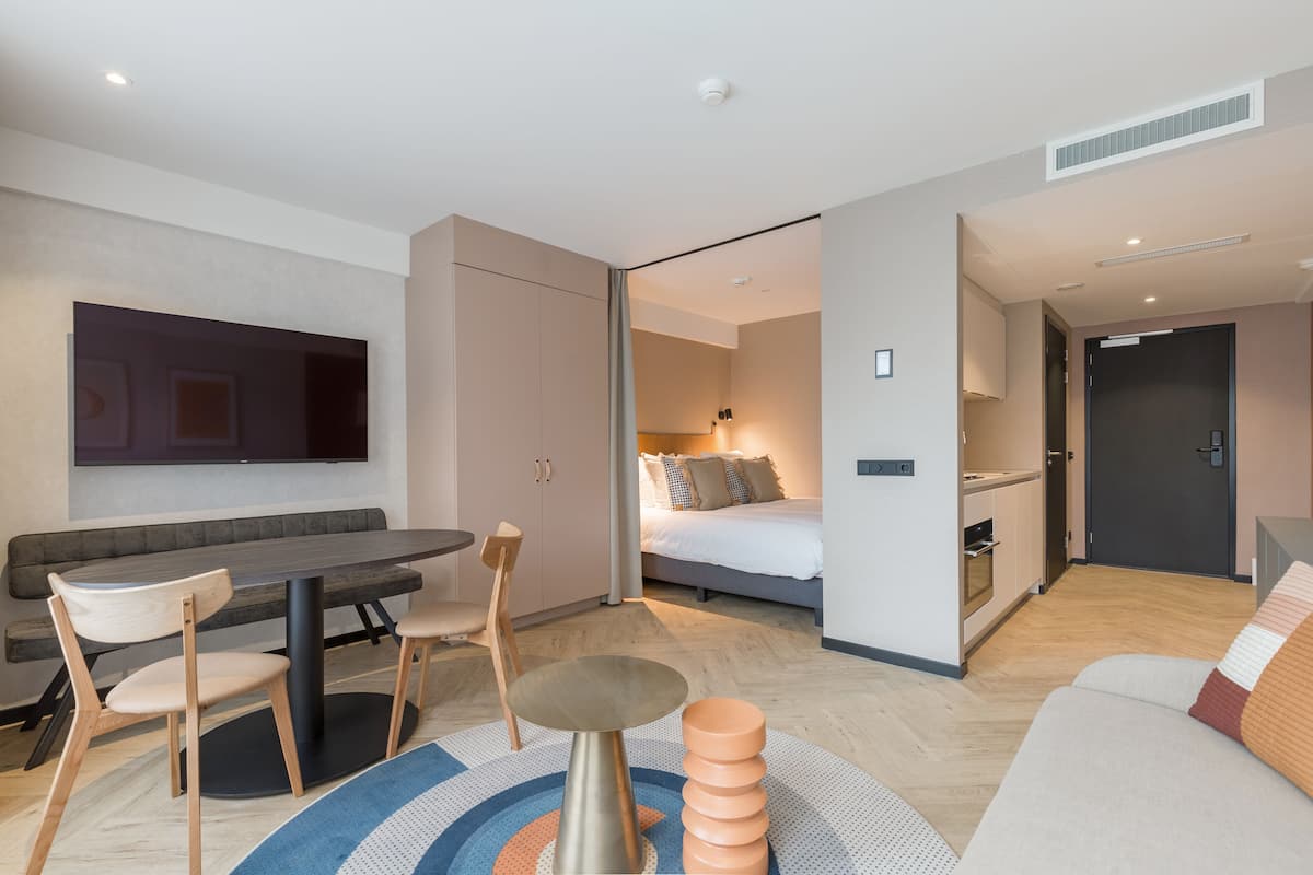 Una habitación de hotel moderna con comedor, cama y kitchenette.