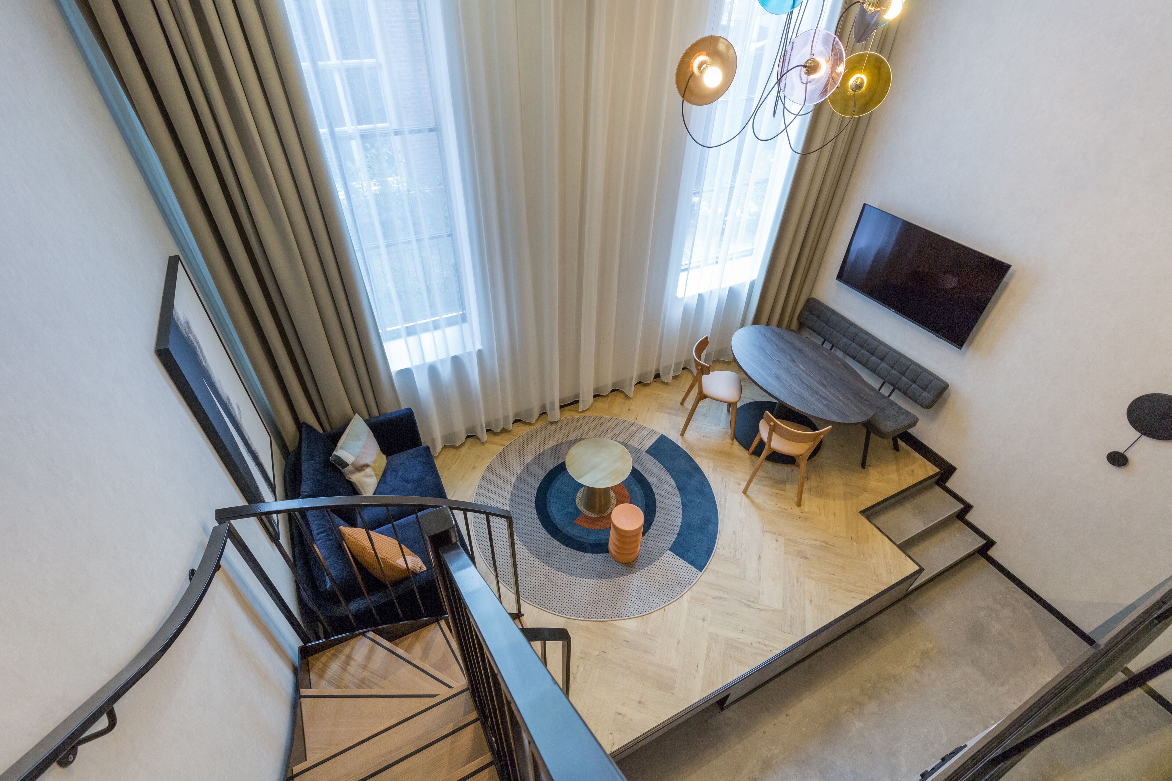 Ein modernes Wohnzimmer mit Treppe, rundem Couchtisch und flachbildschirmfernseher an der Wand.