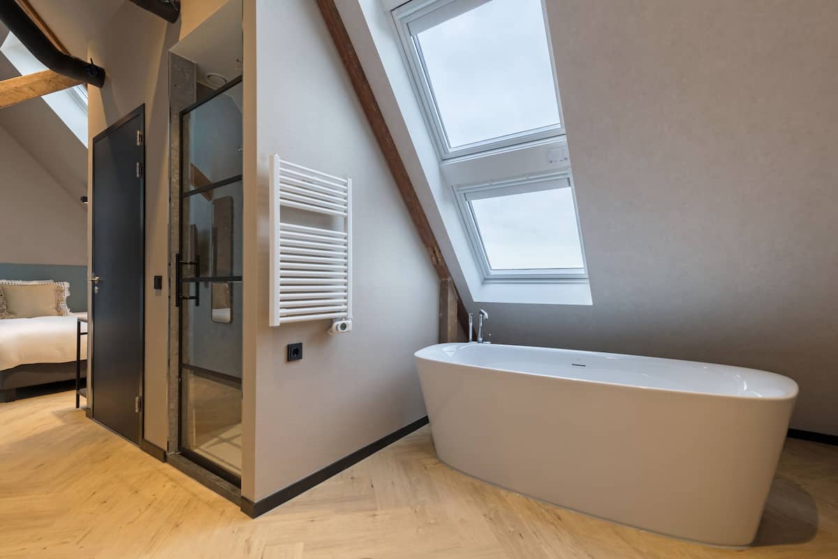 Un baño moderno con bañera independiente, tragaluz y cabina de ducha de vidrio.