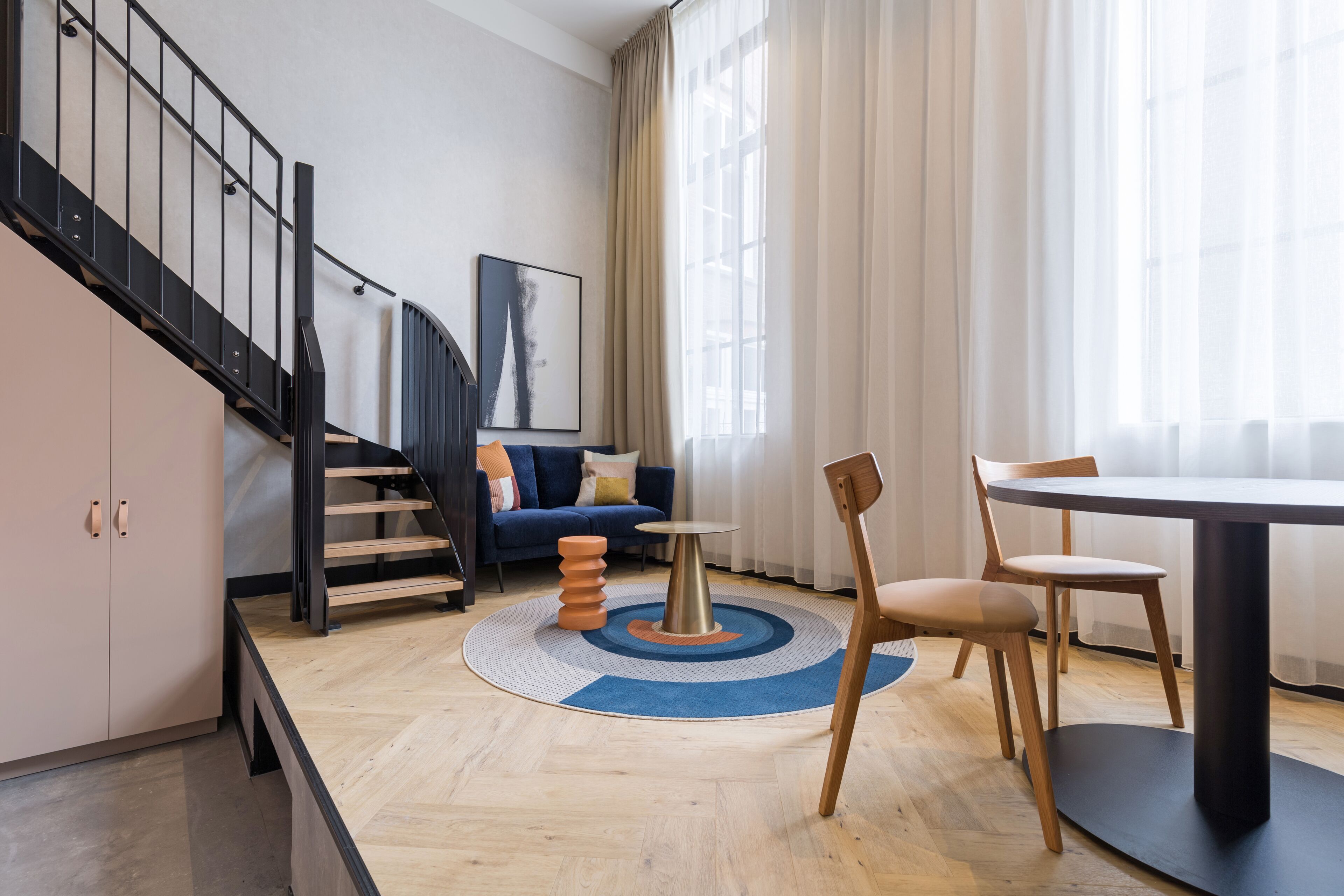 Un salon moderne avec un escalier, une table ronde et un canapé.