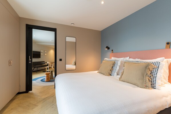 A modern bedroom with a large bed, a mirror, and a view into another room. - Ocean House Scheveningen (The Hague)