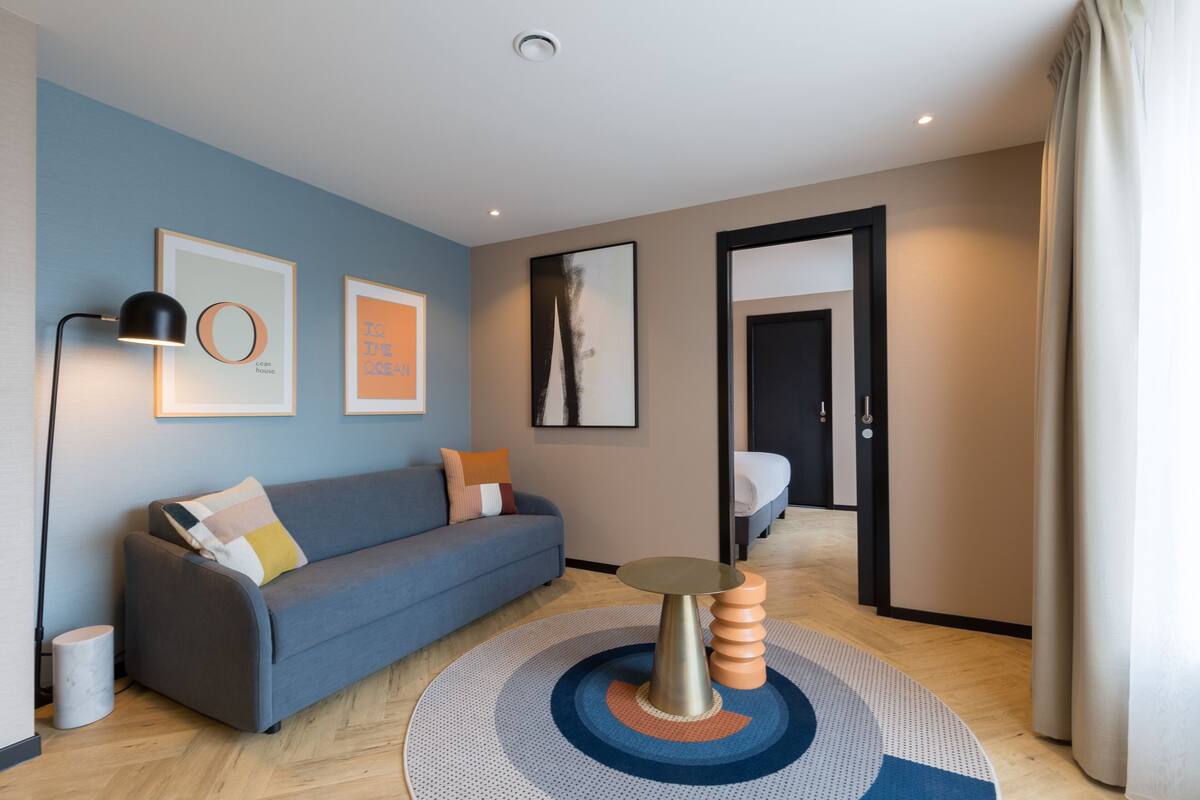 Una sala de estar moderna con un sofá azul, una mesa de centro redonda y cuadros en las paredes.