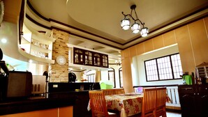 A spacious kitchen with a dining area, featuring a stone wall, wooden cabinets, and a large window.