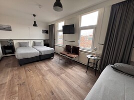 Una habitación de hotel moderna con una cama doble, un sofá, una mesita y un televisor.