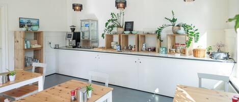 Une cuisine moderne avec des armoires blanches, des comptoirs en bois et des luminaires suspendus. On peut y voir plusieurs plantes et appareils de cuisine.