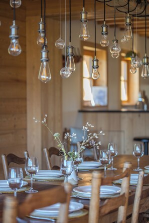 Una mesa de comedor dispuesta con platos, vasos y un jarrón con flores.