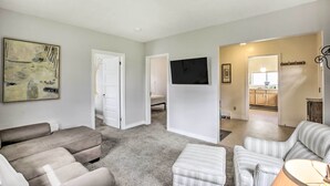 Un salon avec un canapé gris, un fauteuil à rayures et un téléviseur à écran plat fixé au mur.