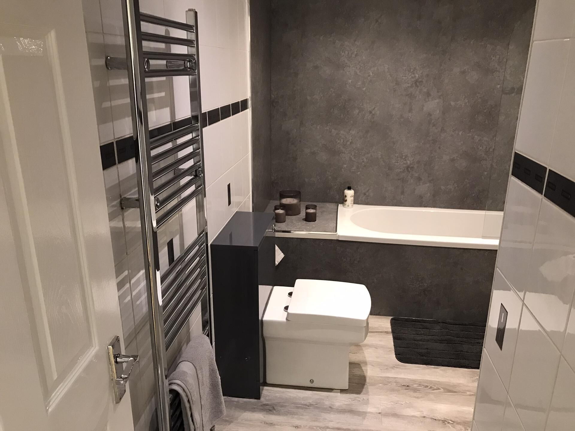 A bathroom with a modern design, featuring a bathtub, a toilet, and a towel rack.