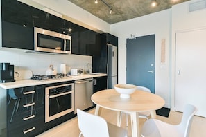 Cozinha moderna com micro-ondas, torradeira e fogão, lava-louças e uma mesa redonda com cadeiras.