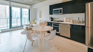 A modern kitchen with a dining area, large windows, and a city view. - King Bed | DT Views | Mins to Stampede | Gym | AC (Calgary)