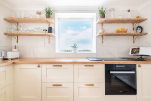 A modern kitchen with wooden countertops, white cabinets, and a window with a view.