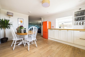 A modern kitchen with white cabinetry, a wooden dining table, and chairs.