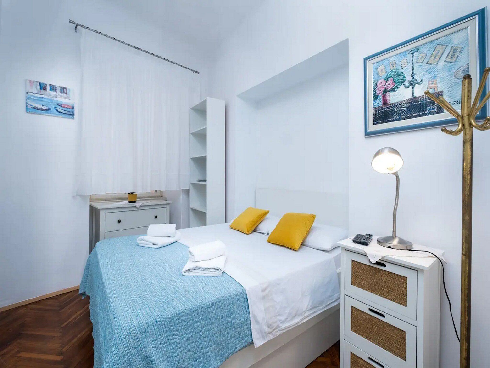 Une chambre à coucher avec un lit, des tables de chevet, une lampe et un tableau au mur.