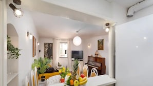 A modern kitchen with a central island, a dining area with a yellow sofa, and a living room with a piano and TV. - Apartment Jany (Dubrovnik)