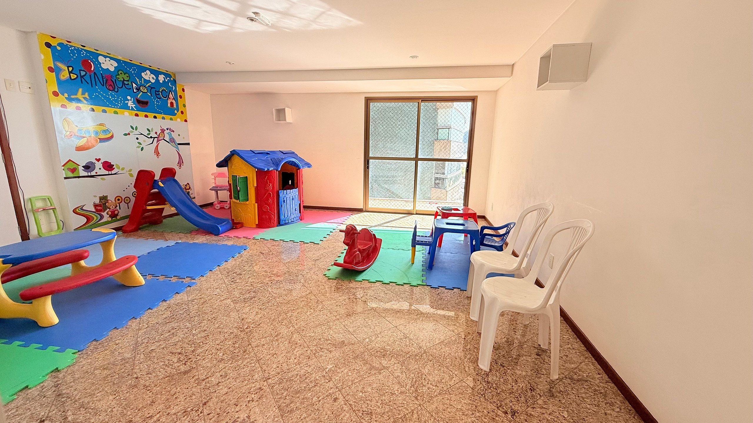 A playroom with a slide, playhouse, and colorful mats.