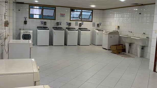 A laundry facility with multiple washing machines and dryers, tiled floors, and a window providing natural light. - Diamond Beach (Vila Velha)
