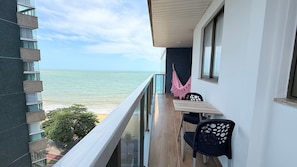 A balcony with a view of the ocean, a table, and two chairs. - Diamond Beach (Vila Velha)
