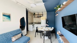 A compact living space with a dining area, kitchenette, and a TV mounted on the wall.