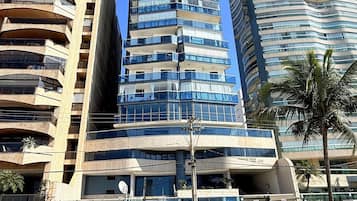 Une rue moderne en milieu urbain, bordée d’immeubles de grande hauteur, avec une zone pavée et quelques piétons.
